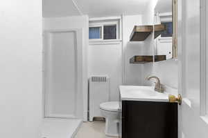 Full bath featuring vanity, radiator heating unit, a stall shower, and light tile patterned flooring