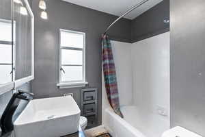 Bathroom with toilet and shower / tub combo with curtain