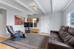 Living room with light wood-style flooring and beamed ceiling