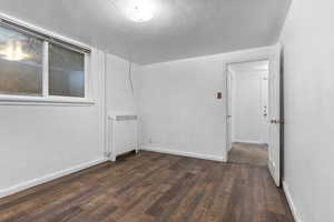 Spare room featuring radiator heating unit and dark wood finished floors