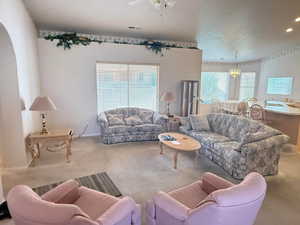 Living room with carpet flooring, healthy amount of natural light, a ceiling fan, and a chandelier