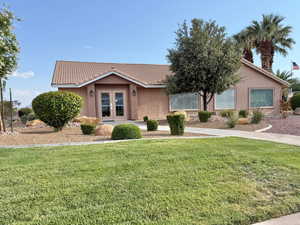 Ranch-style house with stucco siding, a front yard, and a tiled roof