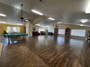 Playroom with pool table, vaulted ceiling, ceiling fan, a textured ceiling, and dark wood-style flooring