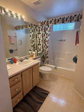 Bathroom with shower / bath combo with shower curtain, vanity, and light flooring