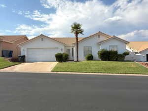 Mediterranean / spanish home featuring a garage, concrete driveway, stucco siding, and a front yard