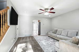 Carpeted living room featuring a ceiling fan, arched walkways, and recessed lighting