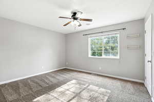 Carpeted spare room featuring baseboards and ceiling fan