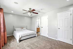Carpeted bedroom with recessed lighting, a ceiling fan, and ensuite bath