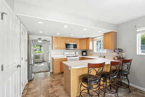 Kitchen featuring a peninsula, light countertops, a breakfast bar area, ceiling fan, and appliances with stainless steel finishes