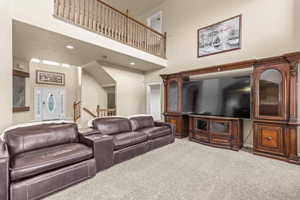 Living area featuring a towering ceiling, carpet, and recessed lighting