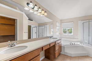 Full bath featuring double vanity, a shower stall, light tile patterned floors, a garden tub, and lofted ceiling