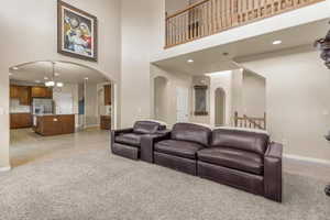 Living room featuring light tile patterned floors, a high ceiling, a chandelier, recessed lighting, and light carpet