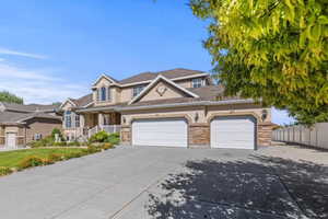 Traditional-style house featuring an attached garage, driveway, a porch, and stone siding