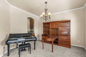 Office featuring ornamental molding, light carpet, arched walkways, and a chandelier