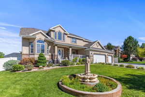 View of front facade featuring stucco siding, a porch, a front lawn, stone siding, and driveway
