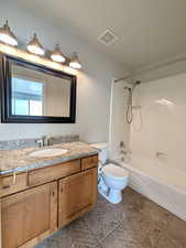 Bathroom featuring bathtub / shower combination, vanity, and dark tile patterned flooring