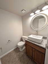 Bathroom with vanity, a textured ceiling, and dark tile patterned floors