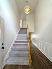 Staircase featuring wood finished floors, a decorative wall, and wainscoting