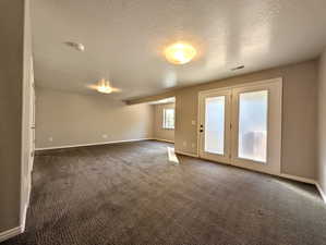 Unfurnished room with dark carpet and a textured ceiling
