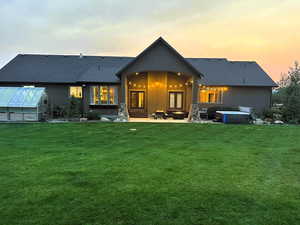 Back of house with a patio, an exterior structure, a lawn, roof with shingles, and an outdoor structure