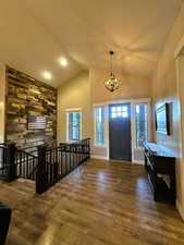 Foyer featuring dark wood finished floors, a chandelier, and high vaulted ceiling