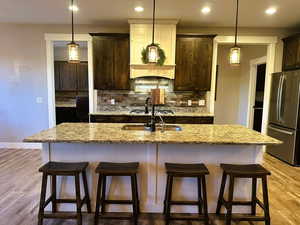 Kitchen with light wood-type flooring, dark brown cabinets, tasteful backsplash, and recessed lighting