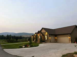 Craftsman inspired home with board and batten siding, an attached garage, concrete driveway, stone siding, and a mountain view