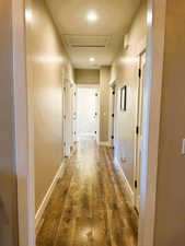 Hallway featuring wood-type flooring, attic access, and recessed lighting