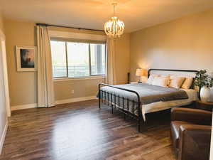 Bedroom with dark wood finished floors, a chandelier, and a textured ceiling