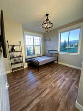 Bedroom featuring dark wood-style flooring, multiple windows, a chandelier, and a textured ceiling