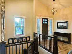 Entrance foyer featuring wood finished floors, high vaulted ceiling, and a chandelier