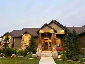 Craftsman inspired home with stone siding, covered porch, a front yard, a shingled roof, and board and batten siding