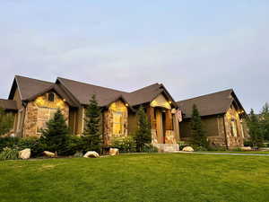 Craftsman house featuring stone siding, a front lawn, and roof with shingles