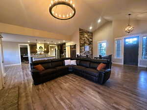 Living room with a chandelier, high vaulted ceiling, dark wood finished floors, and recessed lighting