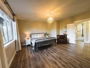 Bedroom featuring dark wood-type flooring, a chandelier, and a textured ceiling