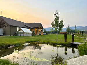 View of green lawn featuring a small pond and a patio