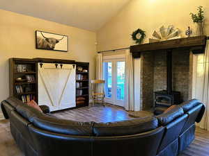 Living area with a wood stove, wood finished floors, and high vaulted ceiling