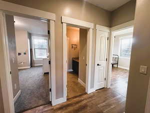 Hallway with dark wood-type flooring and dark carpet