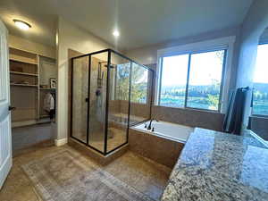 Bathroom featuring a spacious closet, a stall shower, a garden tub, and light tile patterned floors