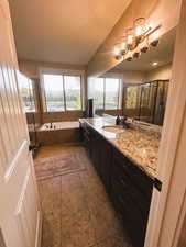 Full bath with vanity, a bath, a stall shower, dark tile patterned flooring, and a textured ceiling