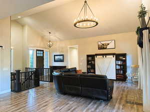 Living room with wood finished floors, high vaulted ceiling, and a chandelier