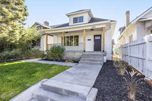 View of front of home with a porch, a front lawn, and roof with shingles