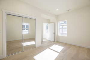 Primary bedroom featuring light wood-type flooring, recessed lighting, and a closet