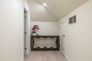 Corridor with lofted ceiling, light wood-style floors, and a textured ceiling