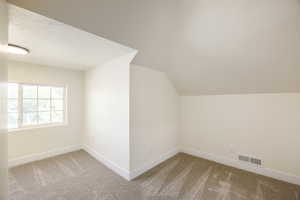 Bonus room with a textured ceiling, carpet floors, and vaulted ceiling