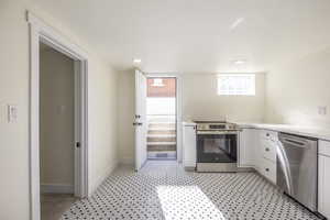 Kitchen with white cabinets, stainless steel appliances, recessed lighting, and light stone counters