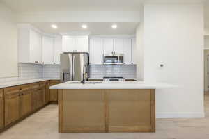 Kitchen featuring brown cabinets, light wood finished floors, appliances with stainless steel finishes, recessed lighting, and tasteful backsplash