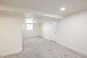 Basement featuring baseboards and light carpet
