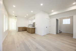 Kitchen featuring light countertops, recessed lighting, light wood-style floors, open floor plan, and brown cabinetry
