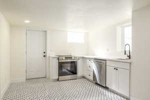 Kitchen with white cabinetry, stainless steel appliances, a textured ceiling, and recessed lighting